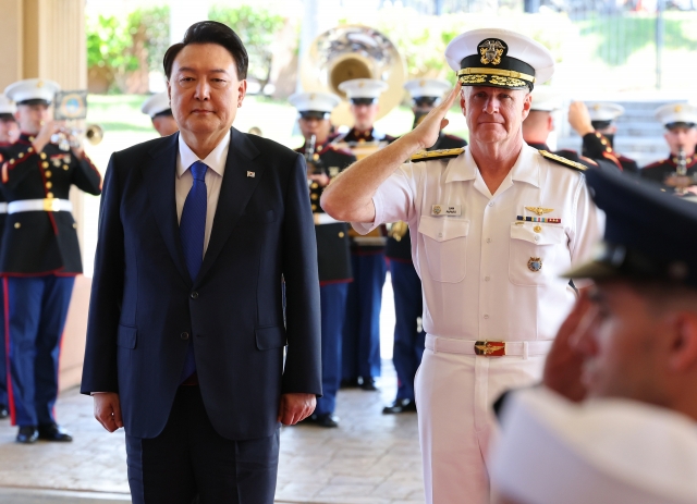 President Yoon Suk Yeol (left) and Adm. Samuel Paparo, commander of the Indo-Pacific Command, salute their countries' national flags during Yoon's visit to Camp Smith, the command's headquarters in Hawaii, on Tuesday. (Yonhap)