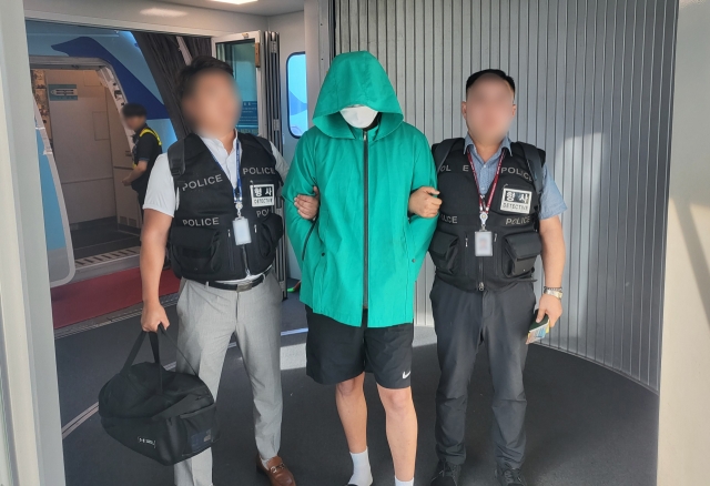 One suspect in the murder of a South Korean tourist in Pattaya, Thailand is escorted off a plane at Incheon International Airport on Wednesday, after being extradited from Phnom Penh, Cambodia where he was apprehended by local police. (Yonhap)