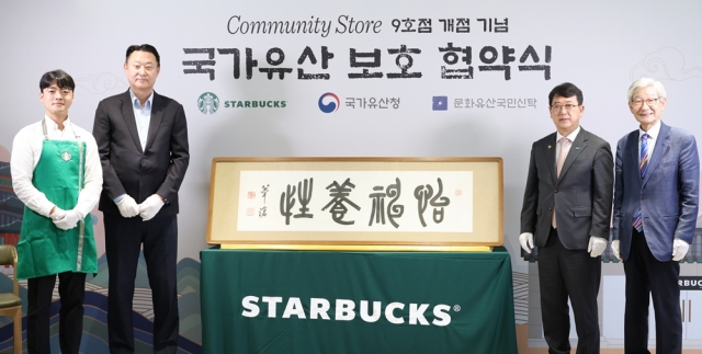 Starbucks Korea CEO Sohn Jeong-hyun (second from left), Korea Heritage Service Administrator Choi Eung-chon (third from left), and National Trust for Cultural Heritage Chief Director Kim Jong-gyu (fourth from left) pose for a photo with the handwritten calligraphy by Oh Se-chang during a ceremony held at the Starbucks Hwangudan branch in Seoul on Thursday. (Starbucks Korea)