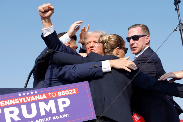 Republican candidate Donald Trump is seen with blood on his face surrounded by Secret Service agents as he is taken off the stage at a campaign event at Butler Farm Show Inc. in Butler, Pennsylvania, Saturday. (AFP-Yonhap)