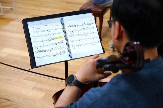 Dodo Cello Orchestra leader Kim Jae-uk looks at a musical score during a regular practice session of the orchestra at Seoul Community Cultural Center Seogyo in Mapo-gu, western Seoul. (Lee Si-jin/The Korea Herald)