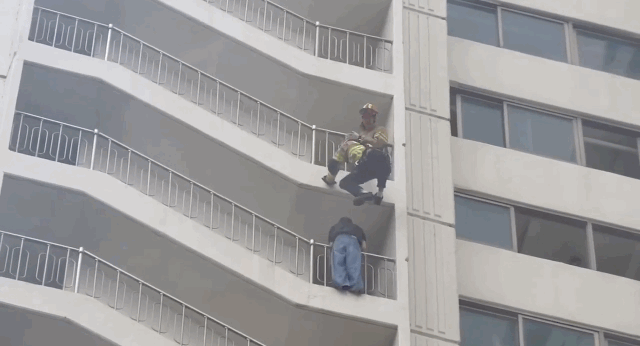 Firefighter Shin Gang-min rescues the woman hanging from the railing on Tuesday in Jeonju, North Jeolla Province. (Jeonbuk Fire Headquarters)