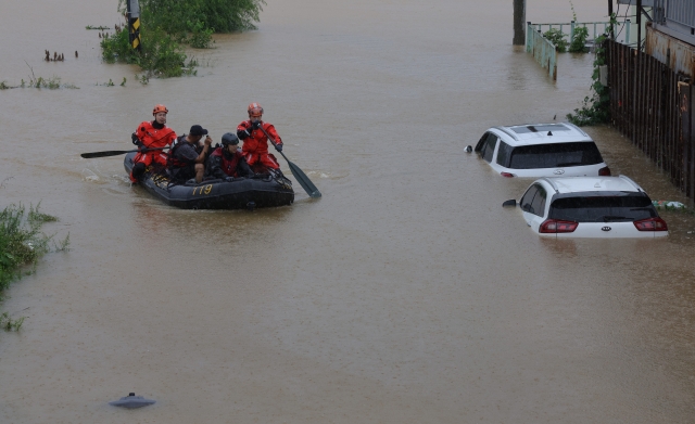 Firefighters rescue stranded factory workers at Paju, Gyeonggi Province, Thursday morning. (Yonhap)