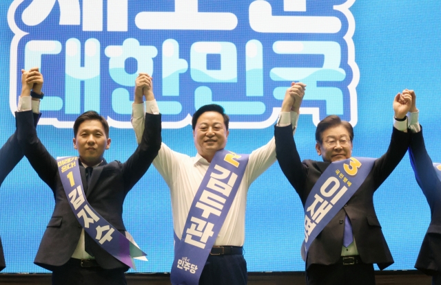 Lee Jae-myung (right) greets people, along with former Interior Minister Kim Doo-gwan (center), during a convention of the Democratic Party to elect a new party leader on the southern island of Jeju on Saturday. (Yonhap)