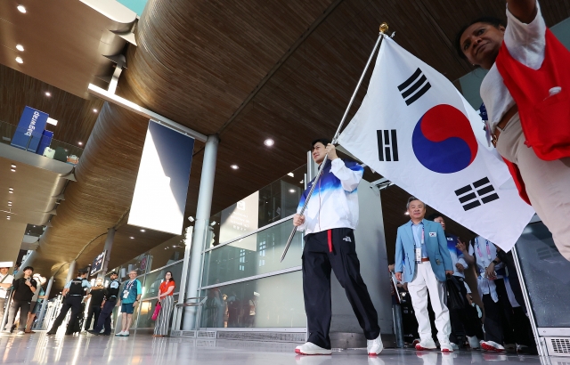 South Korean fencer Gu Bon-gil carries the national flag, Taegeukgi, as the country's main delegation for the Paris Olympics arrives at Paris Charles de Gaulle Airport in Paris on Saturday. (Yonhap)