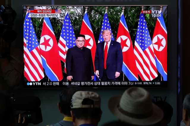 People watch on a screen reporting on the former US President Trump meeting with North Korean leader Kim Jong-un at the Seoul Railway Station on Jun. 12, 2018 in Seoul. (Getty Images)