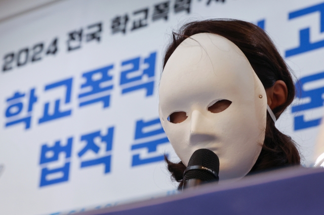 The mother of a school bullying victim, wearing a mask to hide her identity, speaks at a press conference held in Seoul by the Blue Tree Foundation on Wednesday. (Yonhap)