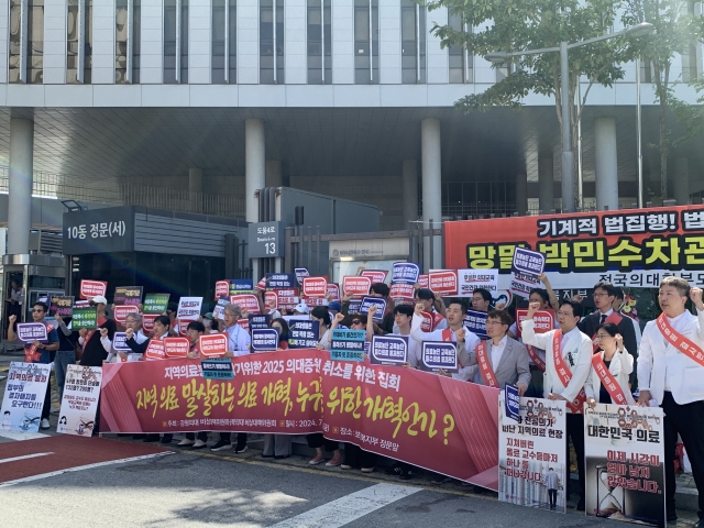 The emergency committees of medical professors at Kangwon National University and Chungbuk National University Hospitals, joined by trainee doctors, medical students and their parents, stage a rally in front of the Health Ministry's complex in the administrative capital of Sejong, urging the government to cancel its planned quota hike for the 2025 school year, Friday. (Korean Medical Association)