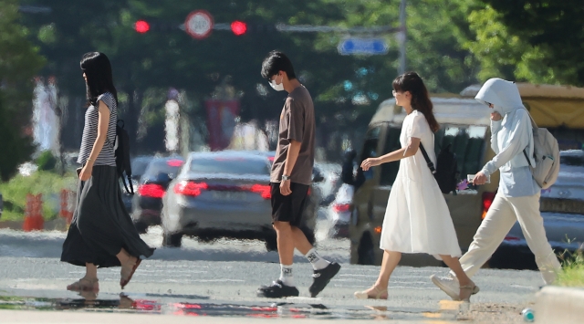 Pedestrians walk amid the heat haze forming above the streets in Busan, Thursday, where daytime temperatures reached 35 degrees Celsius that day. (Yonhap)