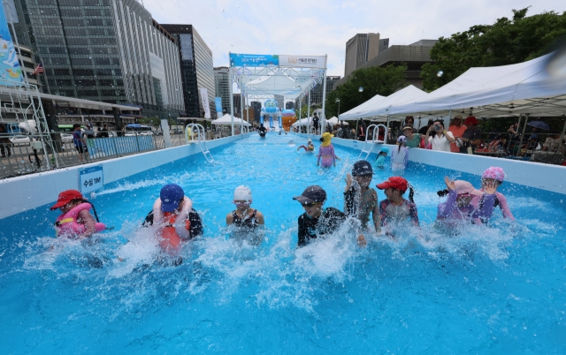 Children splash water at a swimming pool in Gwanghwa Waterpark, installed on Gwangwhamun Plaza, central Seoul on Friday. (Yonhap)