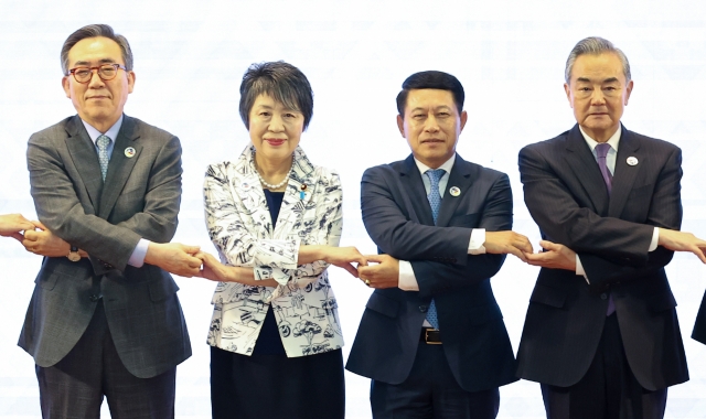 From left: Foreign Minister Cho Tae-yul, Japanese Foreign Minister Yoko Kamikawa, Laotian Foreign Minister Saleumxay Kommasith and Chinese Foreign Minister Wang Yi hold hands for a photo shoot as they attend a foreign ministerial meeting of the ASEAN Plus Three in Vientiane, Laos, on Saturday. (Yonhap)