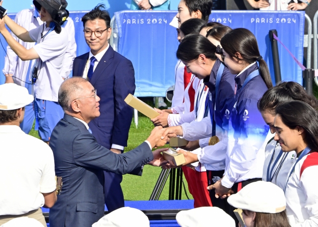 Hyundai Motor Group Executive Chair Chung Euisun (left) shakes hands with Lim Si-hyeon of the South Korean women's archery team after the team won the gold medal in the women's archery team event at the 2024 Summer Olympics in Paris on Sunday. (Korea Archery Association)