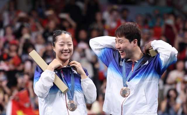 Shin Yu-bin (left) and Lim Jong-hoon of South Korea celebrate after winning the bronze medal in the mixed doubles table tennis event at the Paris Olympics at South Paris Arena 4 in Paris on Tuesday. (Yonhap)