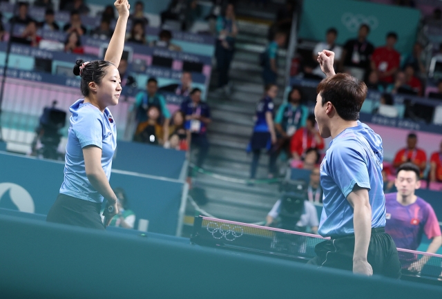 Shin Yu-bin (left) and Lim Jong-hoon cheer after scoring during the third-place match of the mixed doubles table tennis event at the Paris Olympics on Tuesday. (Yonhap)