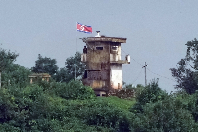 A North Korean soldier stands at the North's military guard post as a North Korean flag flutters in the wind, in this view from Paju, South Korea, on July 24, 2024. (AP)