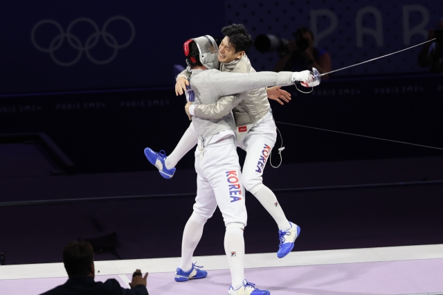 Oh Sang-uk (left) and Gu Bon-gil of South Korea celebrate after winning the gold medal in the men's sabre fencing team event at the Paris Olympics at Grand Palais in Paris on Wednesday. (Yonhap)