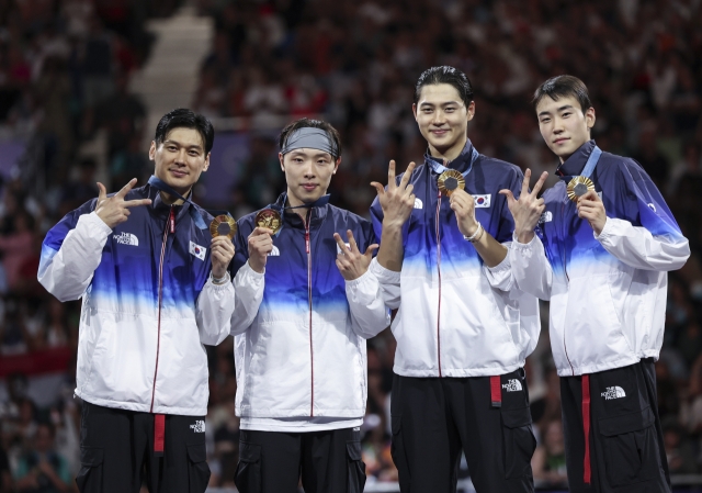 From left: Gu Bon-gil, Park Sang-won, Oh Sang-uk and Do Gyeong-dong of South Korea celebrate after winning the gold medal in the men's saber fencing team event at the Paris Olympics on Wednesday. (Yonhap)