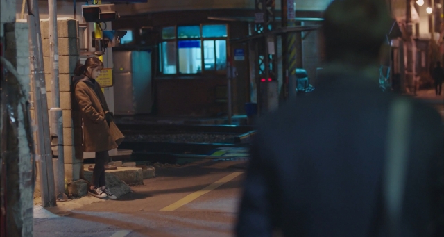 Lee Ji-ahn (played by IU) leans against the wall near the Baekbin Railroad Crossing in 