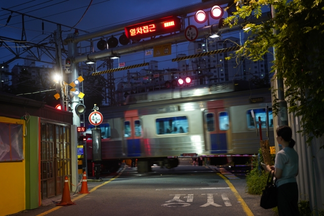 A Seoulite waits for the train to pass at the Baekbin Railroad Crossing in Yongsan-gu, central Seoul, Tuesday. (Lee Si-jin/The Korea Herald)