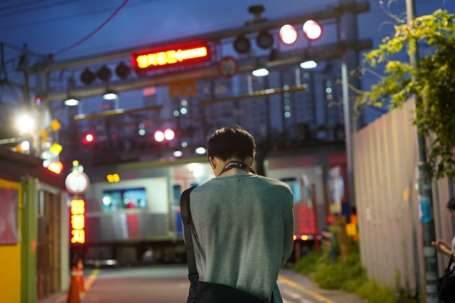 A tourist takes a photo of a subway train passing the Baekbin Railroad Crossing on Tuesday. (Lee Si-jin/The Korea Herald)