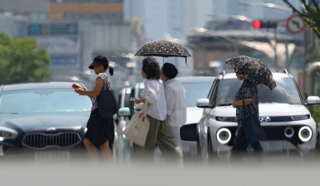 Pedestrians walk amid a heat haze forming above the streets in Daegu, where daytime temperatures reached as high as 36 degrees Celsius on Monday. (Yonhap)