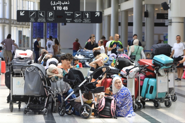 People await their flights at the Beirut International Airport departure hall on Monday. Urgent calls grew for foreign nationals to leave Lebanon, which would be on the front line of a regional war, as Iran and its allies readied their response to high-profile killings blamed on Israel. (AFP)