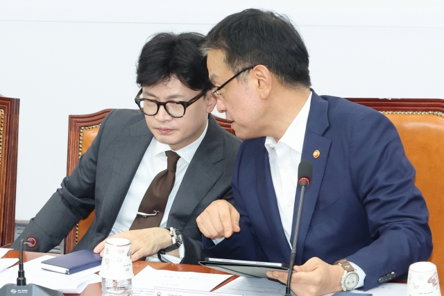 Finance Minister and Deputy Prime Minister Choi Sang-mok, right, whispers to People Power Party Cahir Han Dong-hoon, a policy coordination meeting between the government and the ruling party held at the National Assembly in western Seoul on Tuesday. (Yonhap)