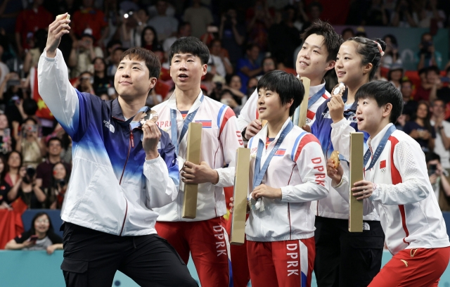 Athletes from South Korea, North Korea and China take a selfie with a Samsung Galaxy Z Flip6 Olympic Edition phone after the table tennis mixed doubles medal matches in Paris on July 30. (Joint Press Corps)