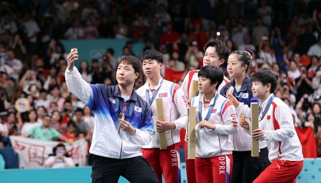 Lim Jong-hoon (left) and Shin Yu-bin (second from right) of South Korea take a selfie using a Samsung-gifted smartphone with their North Korean and Chinese counterparts on the podium during the awards ceremony of the mixed doubles table tennis event at the Paris Olympics at South Paris Arena 4 in Paris on July 30. (Yonhap)