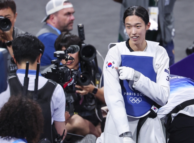 Kim Yu-jin of South Korea points to the national flag, Taegeukgi, on her uniform after winning the gold medal in the women's -57-kilogram taekwondo event at the Paris Olympics at Grand Palais in Paris on Thursday. (Yonhap)