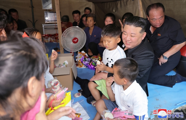 North Korean leader Kim Jong-un (second from right) hugs a child during his visit to a temporary shelter in Uiju County in North Pyongan Province to offer support for their flood damage, in this photo released by the state-run Korean Central News Agency on Saturday. (Yonhap)