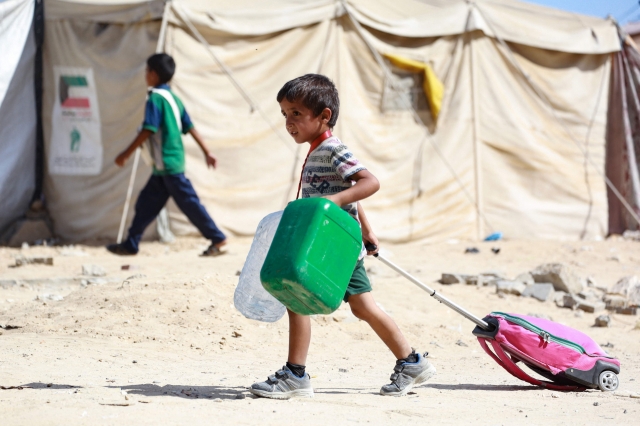 A Palestinian child drags along his bag as people flee the Hamad residential district and its surroundings in Khan Yunis in the southern Gaza Strip after receiving a warning from the Israeli army to evacuate the area on August 11, 2024, amid the ongoing conflict between Israel and the Hamas militant group. (Photo by Bashar TALEB / AFP)