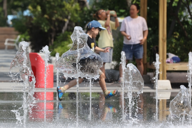 Children cool off in the ground fountain as the heatwave persists across the country, at Gwanghwamun Square in Seoul on Monday. (Yonhap)