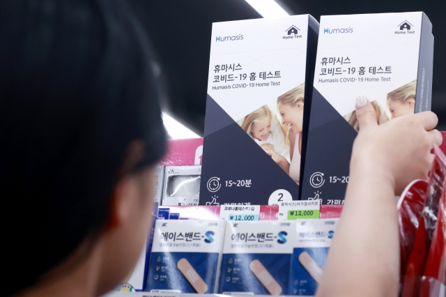 A customer picks up a COVID-19 home test kit at a convenience store in Seoul on Aug. 7. (Yonhap)