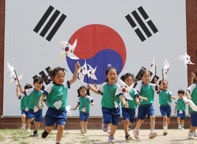 Children run with pinwheels displaying the national flag, known as Taegeukgi, at Seodaemun Prison History Hall in western Seoul on Wednesday, a day before the 79th National Liberation Day. (Yonhap)