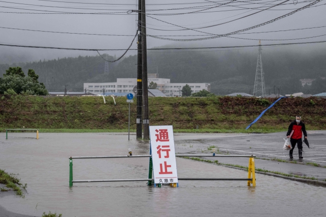 A man walks past a flooded road in the wake of 