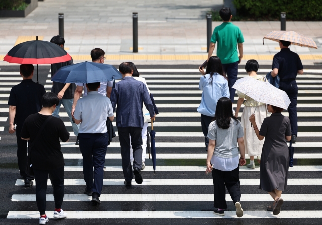 People with parasols cross a street in Jung-gu, Seoul, Aug. 7. (Newsis)