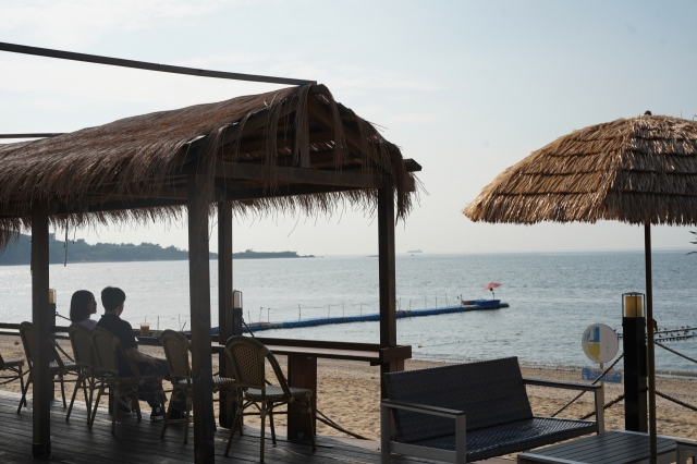 A couple takes a break on the beachfront seating of Hibada Coffee, Aug. 11. (Lee Si-jin/The Korea Herald)