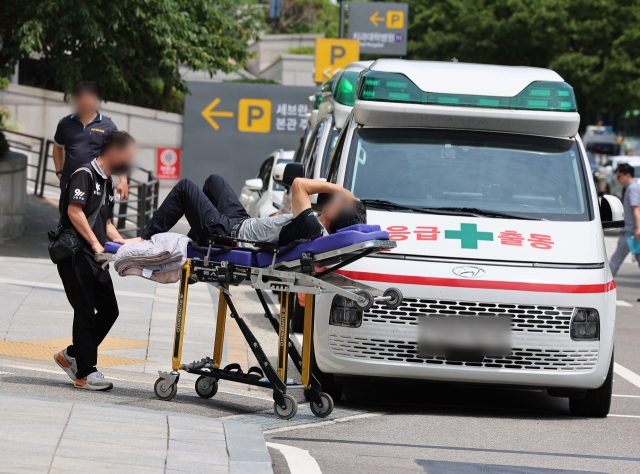 A patient is being moved by an emergency medical technician outside of a Seoul-based hospital on Aug.6. (Yonhap)