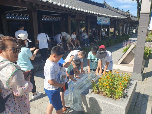 Children touch the large-sized ice blocks installed at Jeonju Hanok Village, in Jeonsu, North Jeolla Province. (Jeonju City)