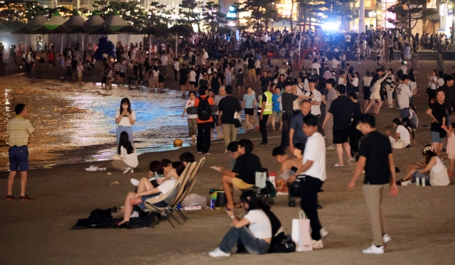 Citizens gathered at Gwangalli Beach in Suyeong-gu, Busan, to cool off and enjoy the sea breeze as the city experienced its longest-ever streak of 21 consecutive tropical nights. (Yonhap)