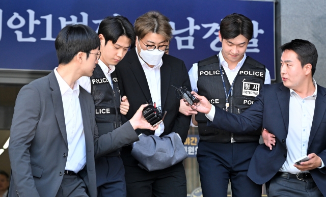 Singer Kim Ho-joong (center) leaves Gangnam Police Station to be escorted to prosecutors on May 31. (Im Se-jun/The Korea Herald)