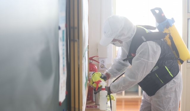 Workers from a disinfection company sanitize an elementary school in Haman, 410 kilometers south of Seoul, on Tuesday. (Yonhap)