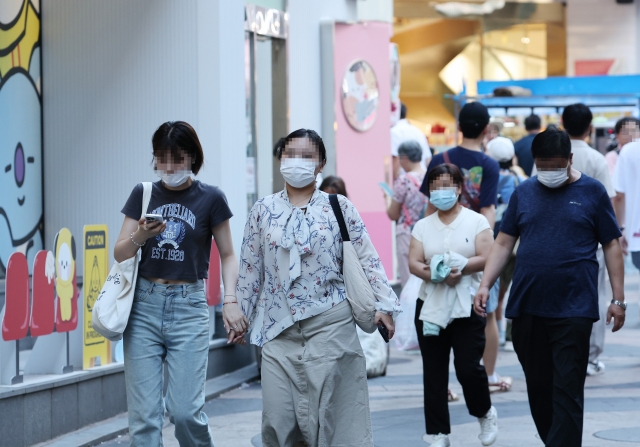 Foreign tourists and local citizens wearing masks walk through the streets of Myeongdong in Seoul on Monday. (Yonhap)