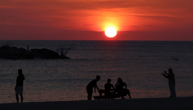 People watch the sunrise on the white sand of Gyeongpo Beach in Gangneung, Gangwon Province, South Korea on Friday. The Korea Meteorological Administration forecast the day's high temperature in Gangneung to reach 36 degrees. (Yonhap)