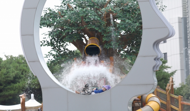 A child sunbathes on top of a sculpture at a water park in Daegu on Sunday. (Yonhap)