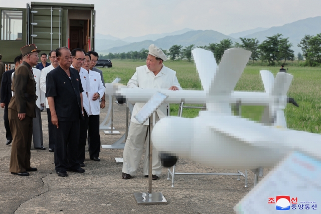 This photo, carried on Monday, shows the North's leader Kim Jong-un (right) inspecting a performance test of drones on Saturday. (KCNA)