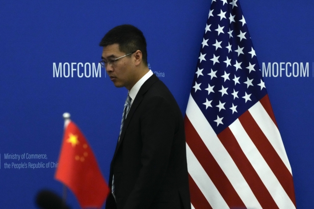 A Chinese official walks by the China and US national flags before a meeting between Commerce Secretary Gina Raimondo and Chinese Minister of Commerce Wang Wentao at the Ministry of Commerce in Beijing on Aug. 28, 2023. (File Pool Photo via AP)