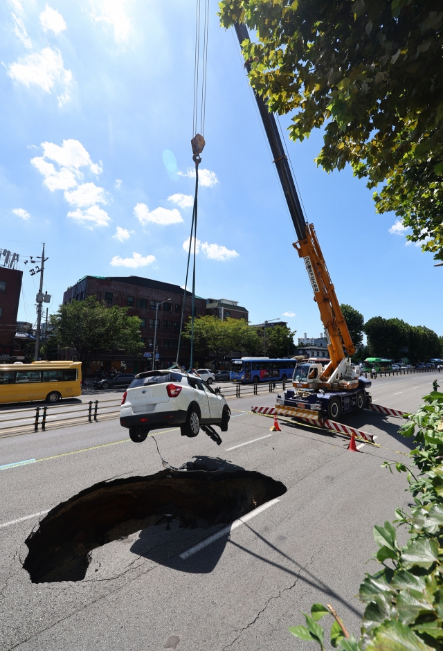 The car is lifted out of the sinkhole in Seoul's Seodaemun-gu via crane, on Thursday. (Yonhap)