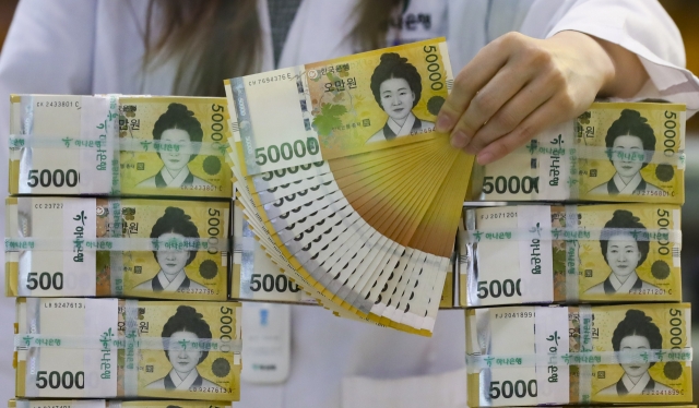 A clerk checks 50,000-won notes at a Seoul bank. (Newsis)